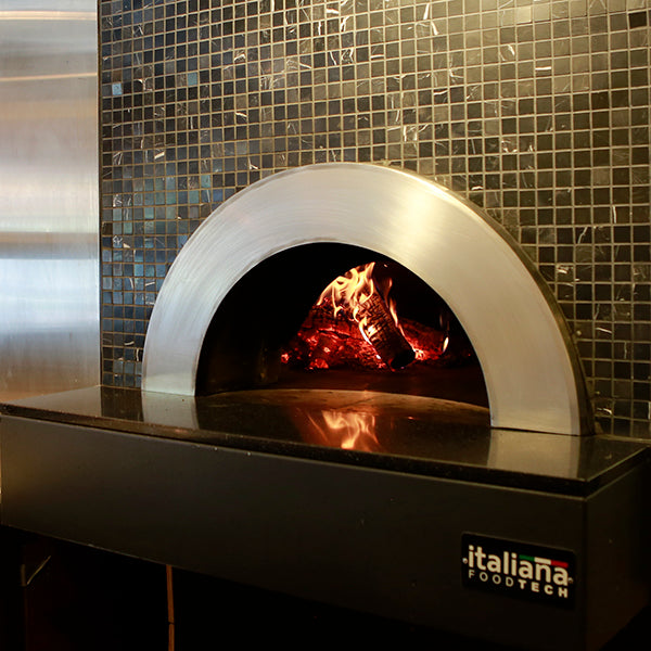 an enclosed Milano fired oven in use, with custom tile pattering around the enclosure.
