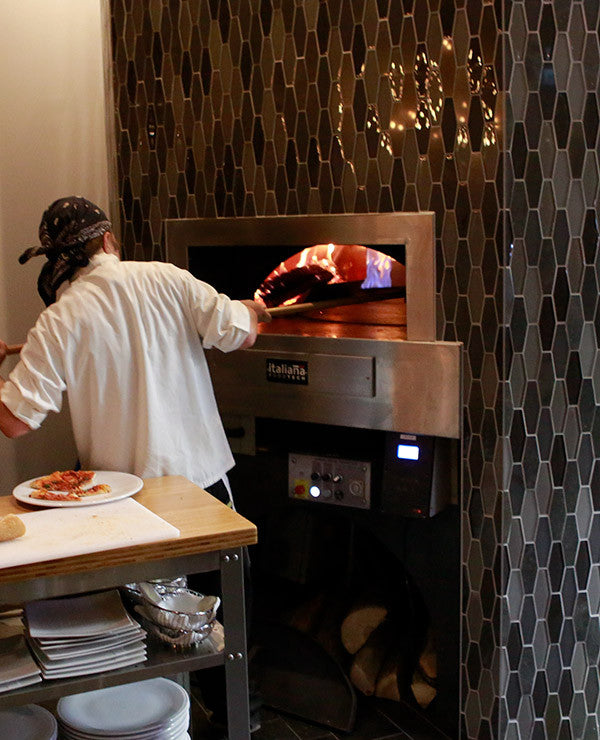 an enclosed Milano fired oven in use, with custom tile pattering around the enclosure.
