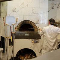 Milano fired oven enclosed within a white marbled wall.